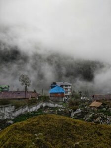 A serene village nestled in a foggy mountain landscape showcasing roofs and greenery.