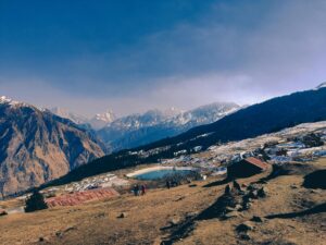 Scenic landscape of Auli, India with snowy mountains and a serene lake in winter.